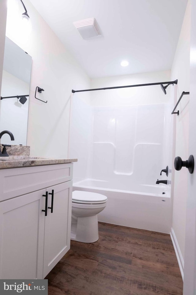 full bathroom with visible vents, toilet, wood finished floors,  shower combination, and vanity