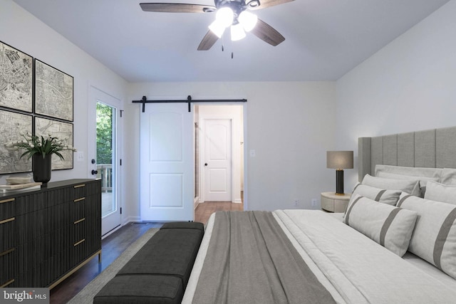 bedroom with ceiling fan, a barn door, and dark wood-type flooring