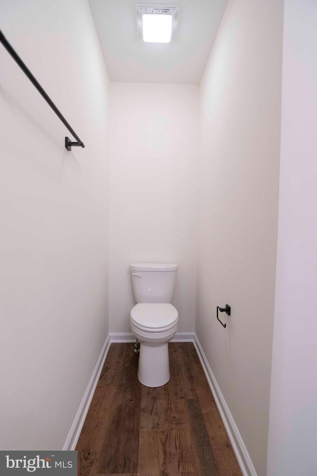 bathroom with toilet, baseboards, and wood finished floors