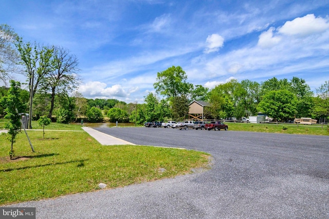 view of home's community featuring uncovered parking and a yard