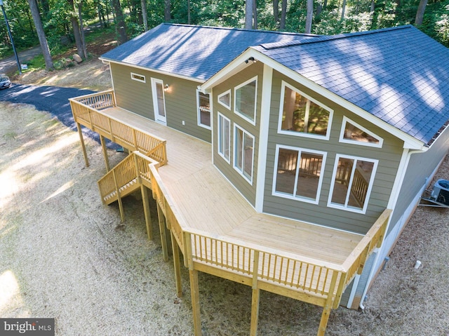 rear view of house featuring roof with shingles and a wooden deck