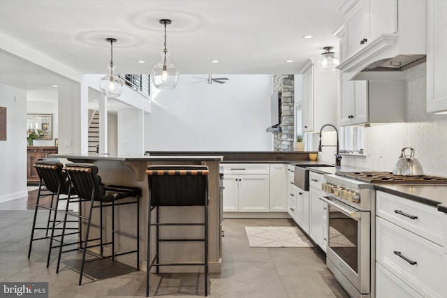 kitchen with high end range, decorative light fixtures, a kitchen bar, white cabinetry, and sink