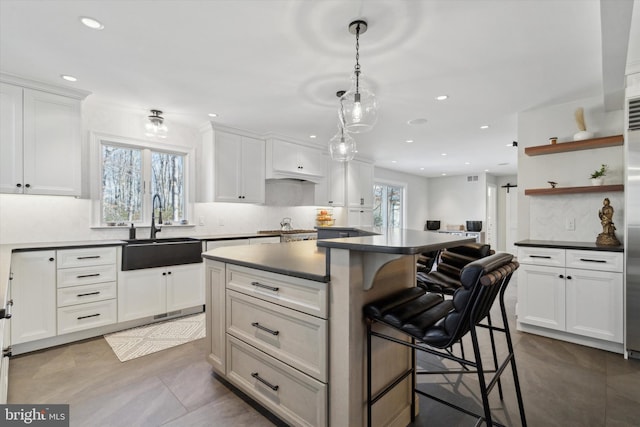 kitchen featuring a kitchen island, a kitchen bar, white cabinetry, and sink