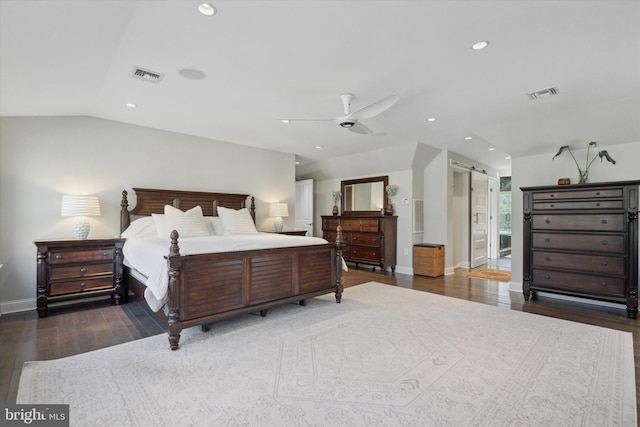 bedroom featuring ceiling fan, vaulted ceiling, a barn door, and dark hardwood / wood-style floors