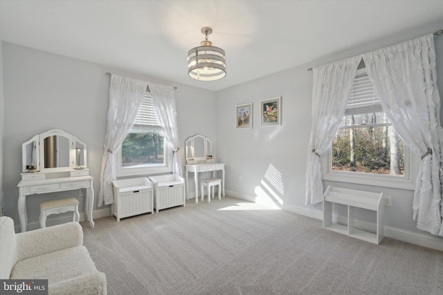 living area featuring plenty of natural light, a notable chandelier, and light colored carpet