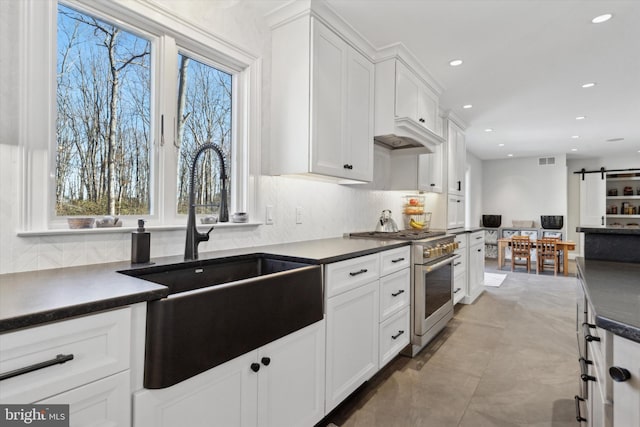 kitchen featuring sink, white cabinetry, a barn door, and high end range