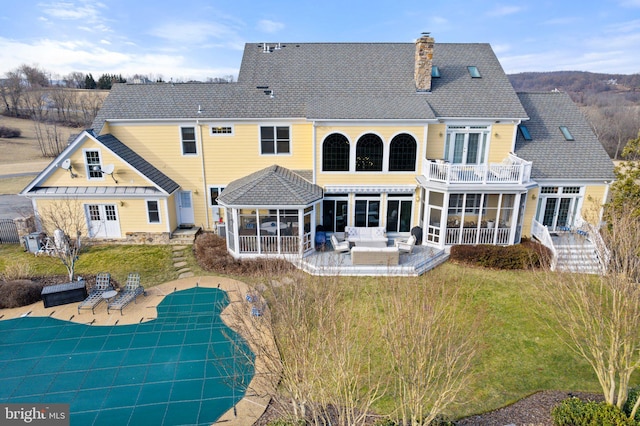 back of house with french doors, a chimney, outdoor lounge area, a balcony, and a patio area