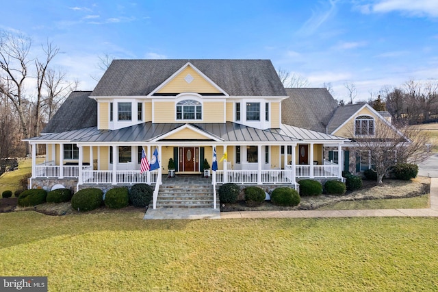 view of front of house with roof with shingles, a porch, a front yard, and a standing seam roof