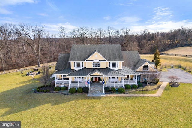 farmhouse featuring a standing seam roof, covered porch, and a front lawn