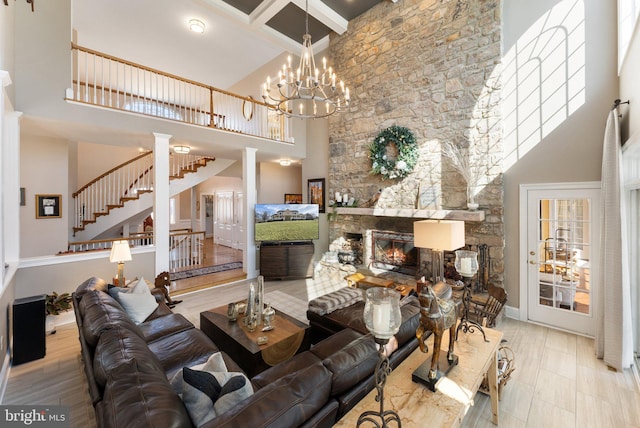 living room with beam ceiling, a high ceiling, a fireplace, stairs, and a chandelier