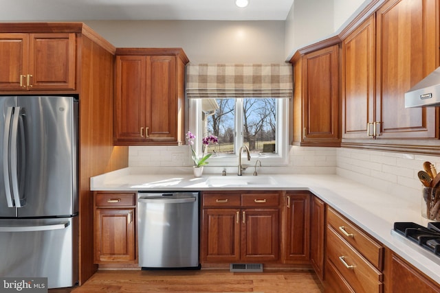 kitchen featuring a sink, stainless steel appliances, visible vents, and brown cabinetry