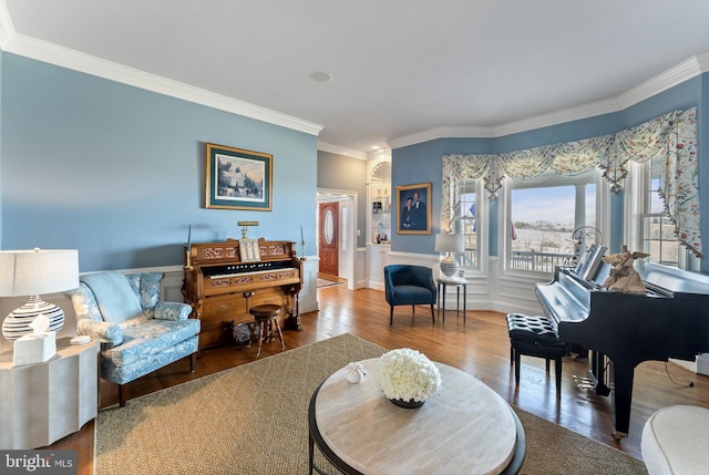 living area featuring a decorative wall, wood finished floors, a wainscoted wall, and ornamental molding