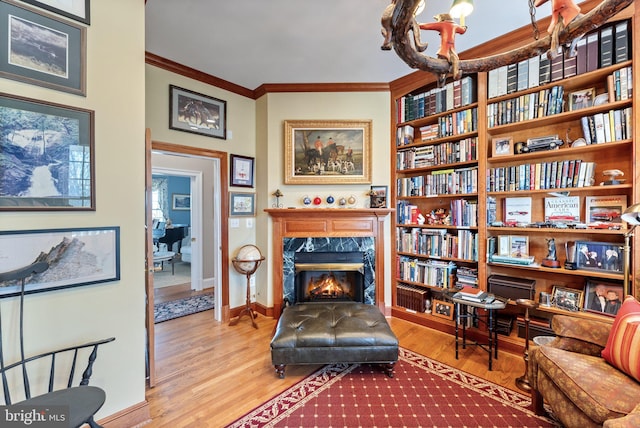 sitting room with crown molding, wood finished floors, and a premium fireplace