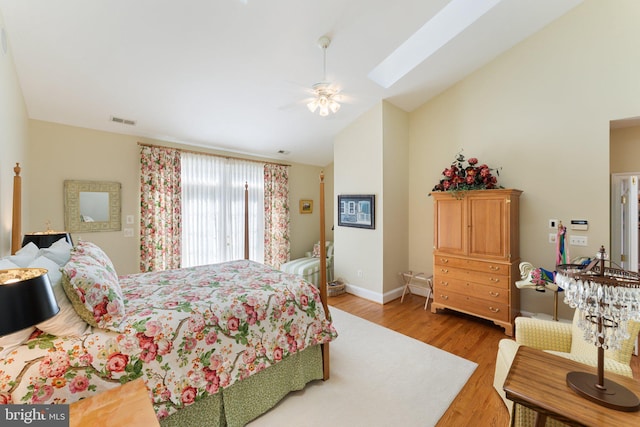 bedroom with lofted ceiling with skylight, wood finished floors, visible vents, and baseboards