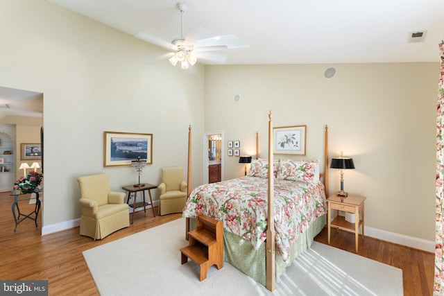 bedroom with visible vents, vaulted ceiling with skylight, baseboards, and wood finished floors