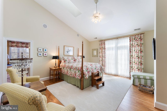 bedroom featuring visible vents, multiple windows, baseboards, and wood finished floors