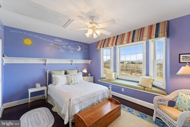 bedroom featuring a ceiling fan, attic access, wood finished floors, and baseboards