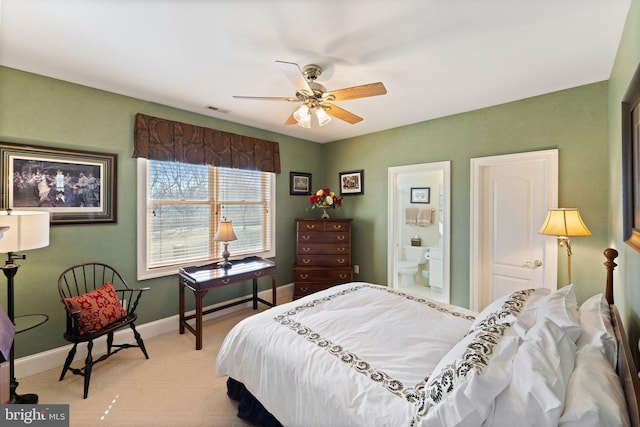 bedroom featuring visible vents, baseboards, light carpet, and ensuite bath