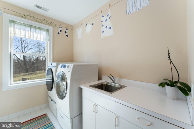 laundry room with visible vents, a sink, washer and dryer, cabinet space, and light tile patterned flooring