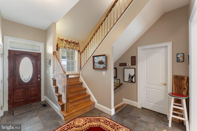 entryway with stairway, baseboards, and stone finish flooring