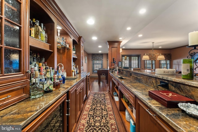 bar featuring dark wood finished floors, decorative columns, recessed lighting, wet bar, and a sink