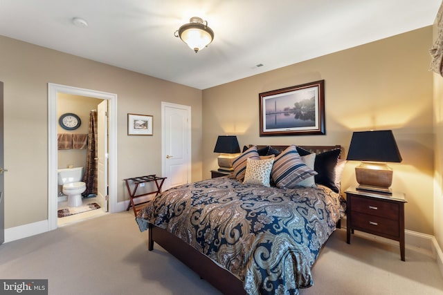 carpeted bedroom with ensuite bath and baseboards