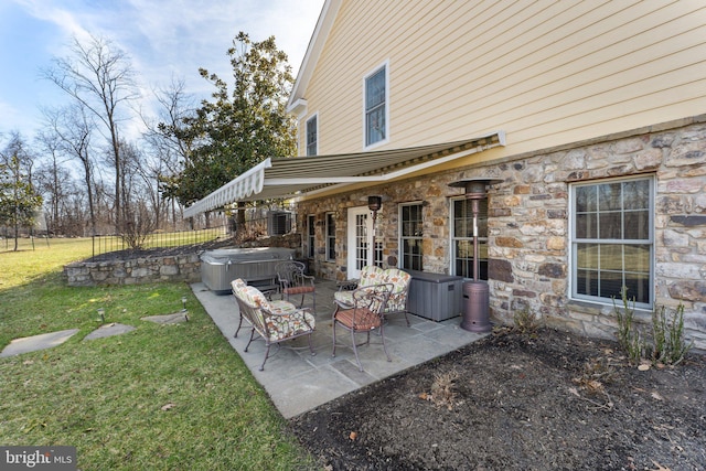 view of patio with a hot tub and fence