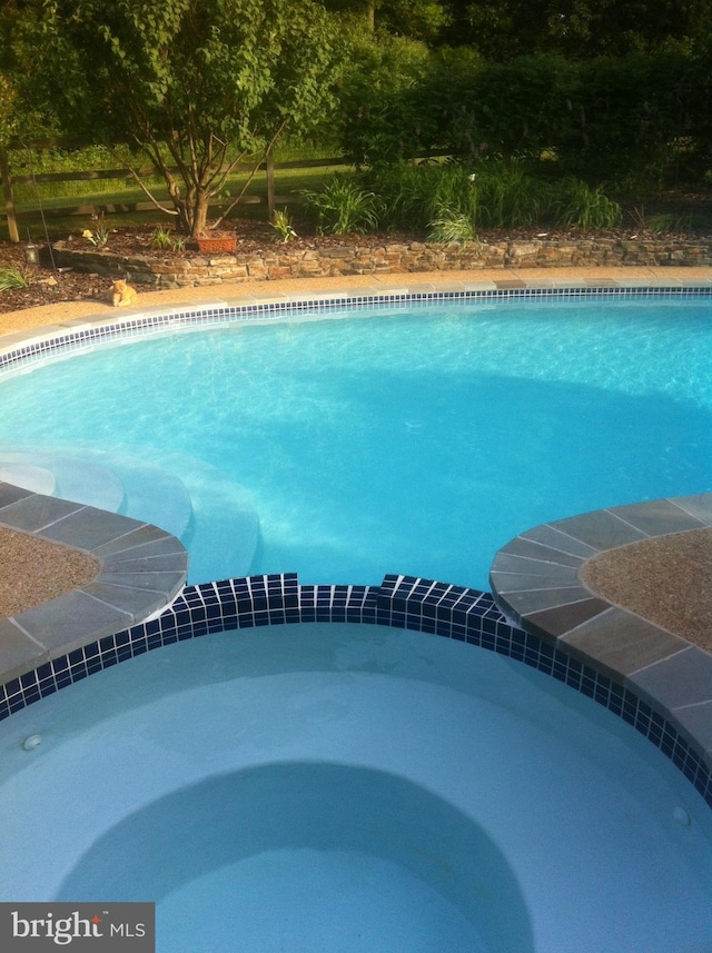 view of pool with a pool with connected hot tub