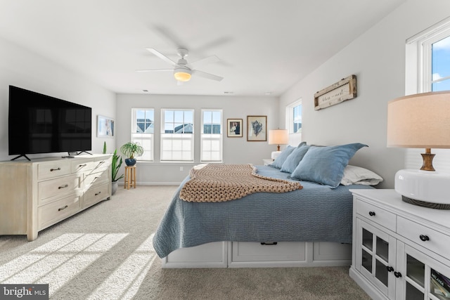 bedroom featuring ceiling fan, light carpet, and multiple windows