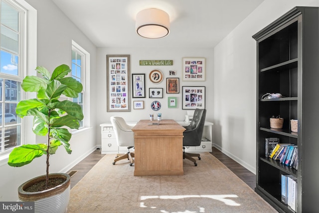 home office with plenty of natural light and dark hardwood / wood-style floors