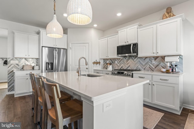 kitchen featuring stainless steel appliances, decorative light fixtures, white cabinets, and sink