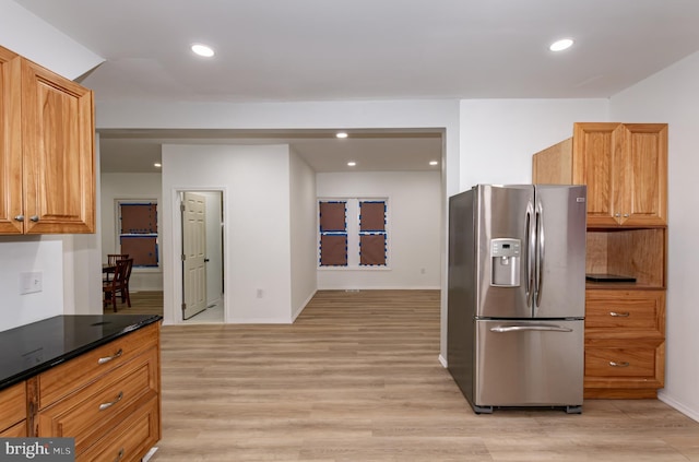 kitchen with stainless steel refrigerator with ice dispenser, dark stone countertops, and light wood-type flooring