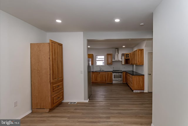 kitchen with stainless steel appliances, dark wood-type flooring, wall chimney exhaust hood, and sink