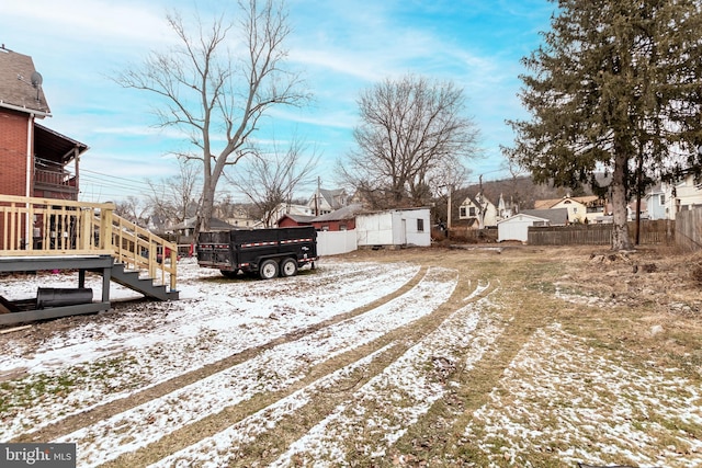 yard layered in snow featuring a wooden deck and a shed