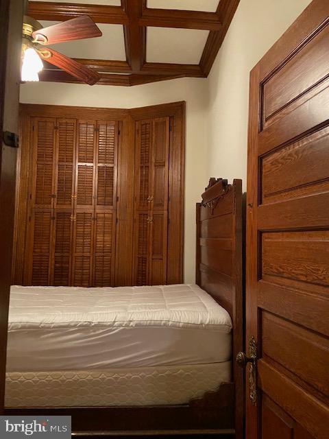 unfurnished bedroom featuring beam ceiling, ceiling fan, and coffered ceiling