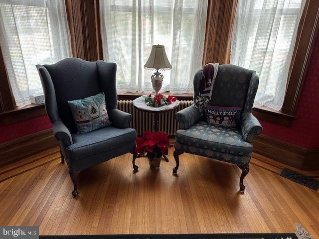 sitting room with radiator heating unit, a wealth of natural light, and wood-type flooring