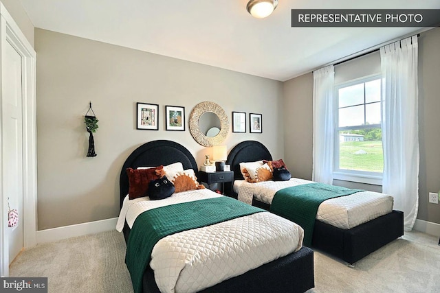 bedroom with light colored carpet and baseboards