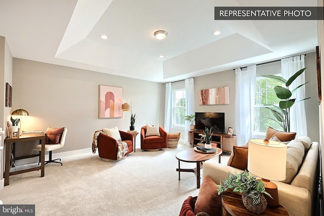 living room featuring light carpet, recessed lighting, baseboards, and a tray ceiling