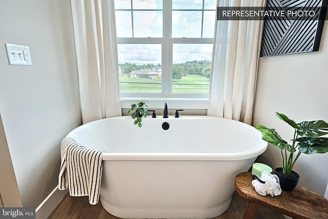 bathroom featuring a freestanding bath and wood finished floors