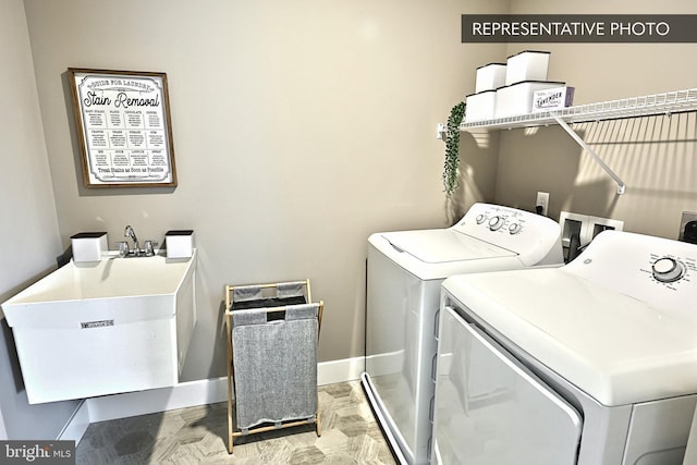 clothes washing area with washing machine and clothes dryer, laundry area, baseboards, and a sink