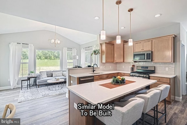 kitchen featuring a sink, decorative backsplash, light countertops, vaulted ceiling, and stainless steel appliances