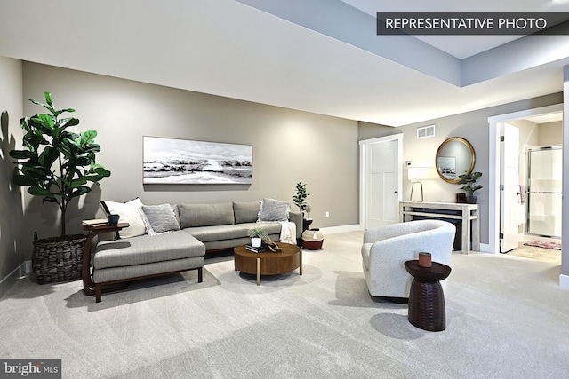 carpeted living area featuring visible vents and baseboards