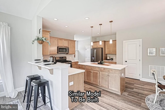 kitchen featuring hardwood / wood-style floors, kitchen peninsula, stainless steel appliances, decorative backsplash, and decorative light fixtures