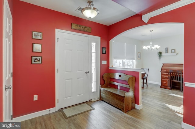 foyer entrance featuring a notable chandelier, light hardwood / wood-style flooring, and a wealth of natural light