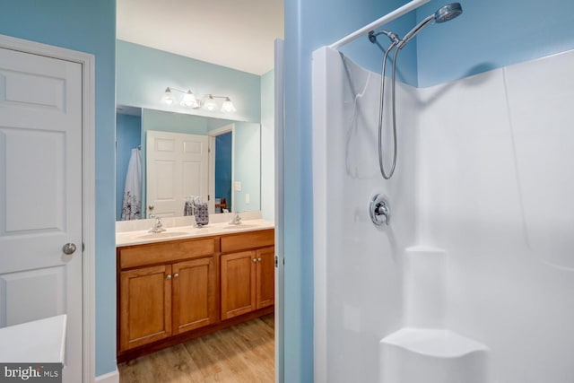 bathroom with walk in shower, wood-type flooring, and vanity