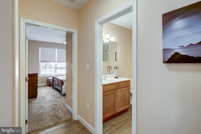 corridor with light hardwood / wood-style floors and sink