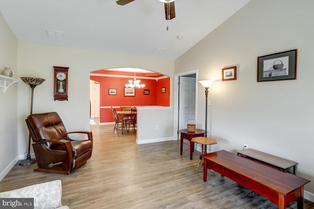 sitting room with ceiling fan with notable chandelier, vaulted ceiling, and light hardwood / wood-style flooring