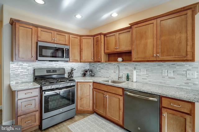 kitchen with light stone countertops, appliances with stainless steel finishes, backsplash, and sink