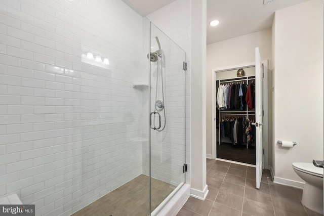 bathroom featuring toilet, tile patterned floors, and a shower with door