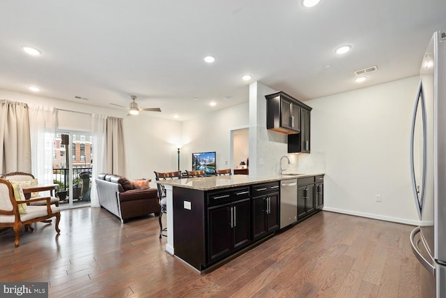 kitchen featuring a kitchen bar, backsplash, dark hardwood / wood-style flooring, and stainless steel appliances